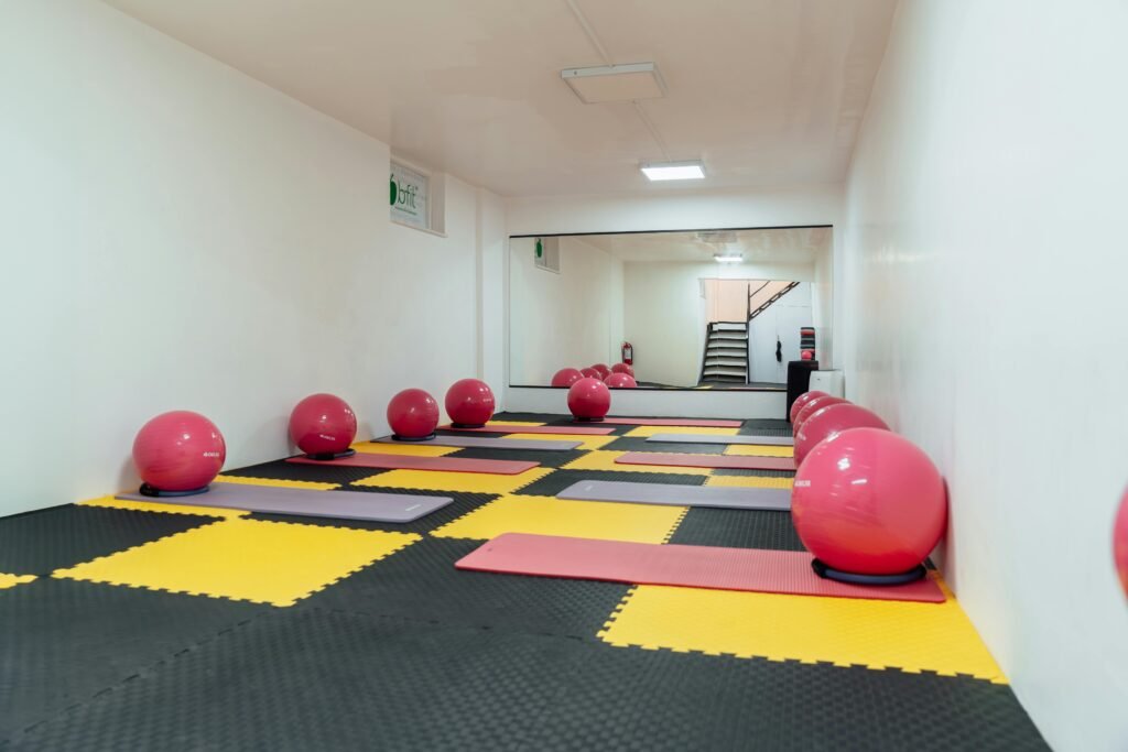 A modern gym interior featuring pink exercise balls and yellow mats, ideal for fitness classes.