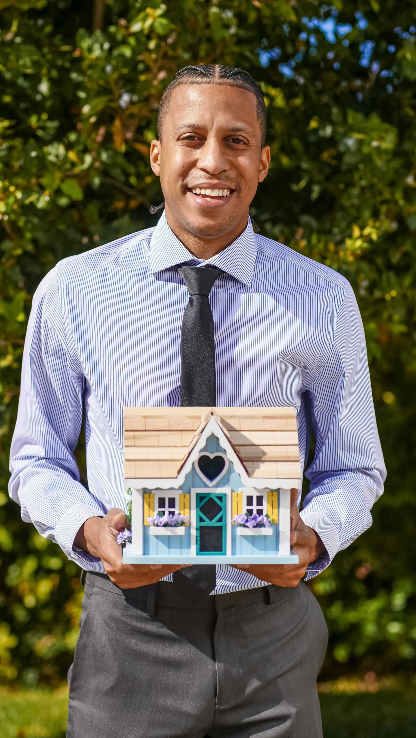 Professional realtor holding a small house model, symbolizing real estate and new home purchases.